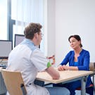 Patiënt zit op stoel aan tafel, aan de andere kant zit een dokter met medisch voorwerp in zijn hand. Ze zijn in gesprek. Maag-Darm-Lever (MDL) afdeling voor preventie, onderzoek en behandeling van aandoeningen van het spijsverteringsstelsel